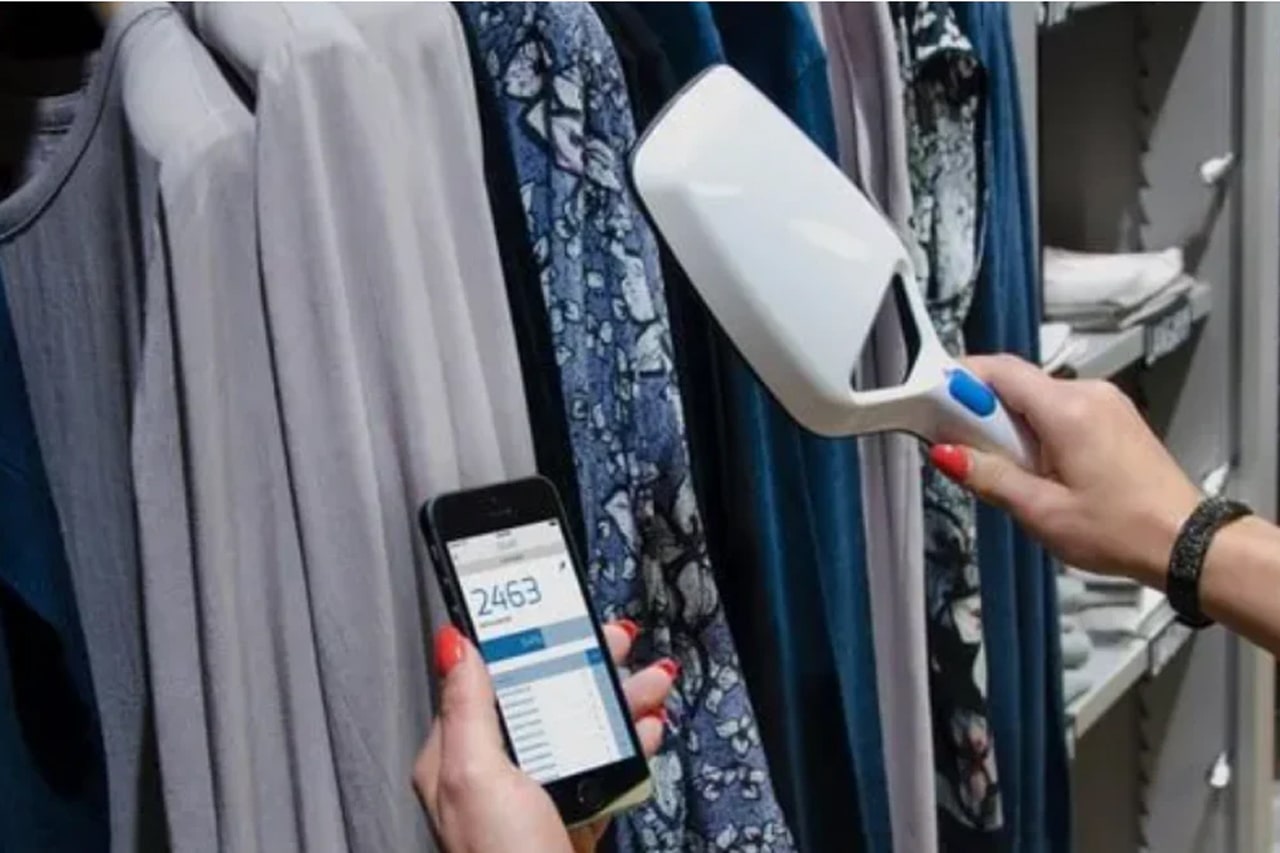 Person scanning clothing with an RFID reader while monitoring data on a smartphone
